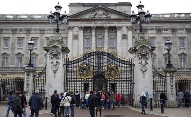 Tourists are photographed at the gates of Buckingham Palace.
